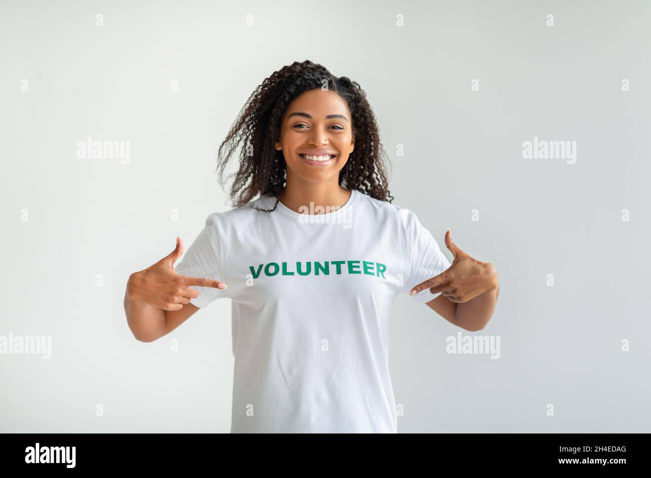 Jeune femme afro-américaine montrant un t-shirt volontaire et souriant, se pointant avec les doigts fiers et heureux Banque D'Images