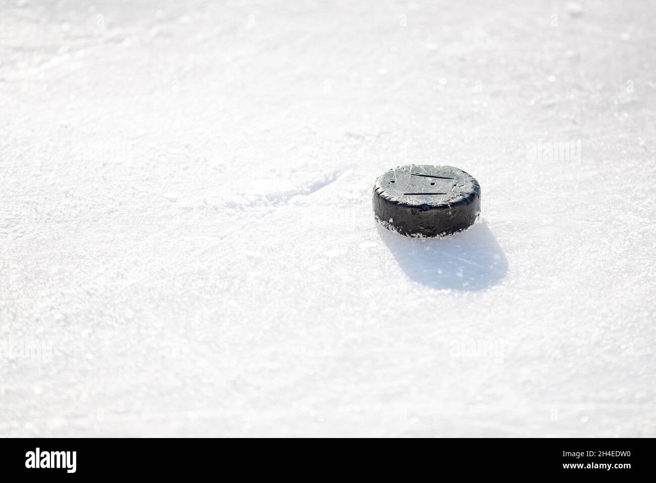 Vieux palet de hockey sur glace posé dans la patinoire couverte de neige Banque D'Images