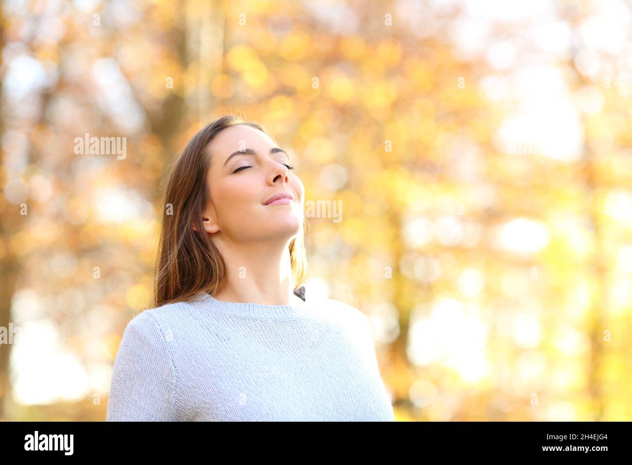 Bonne femme détendue respirant de l'air frais en automne dans une forêt Banque D'Images