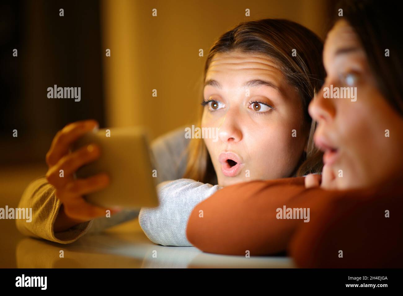 Deux amis survenaient la nuit à la maison pour vérifier le contenu d'un smartphone Banque D'Images