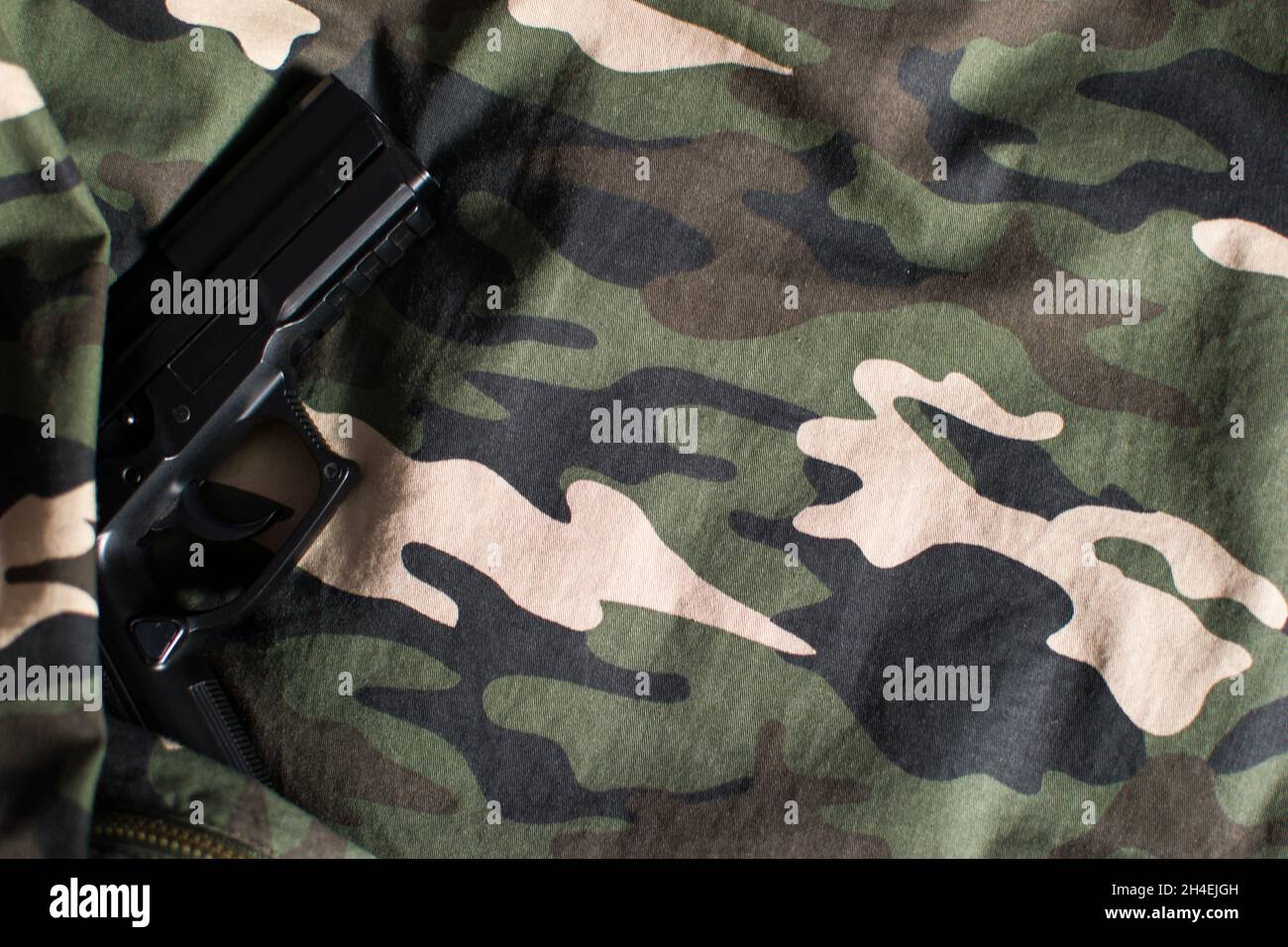 Pistolet noir sur fond uniforme militaire camouflage avec espace de copie Banque D'Images