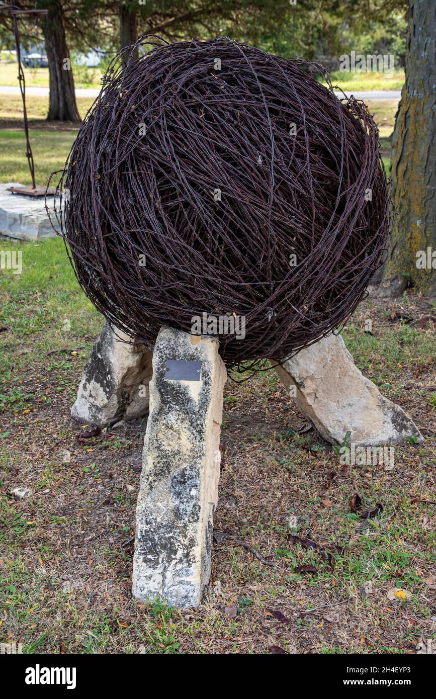 Une grande boule de barbelés marron, rouillée, exposée à l'extérieur du musée des barbelés. Banque D'Images