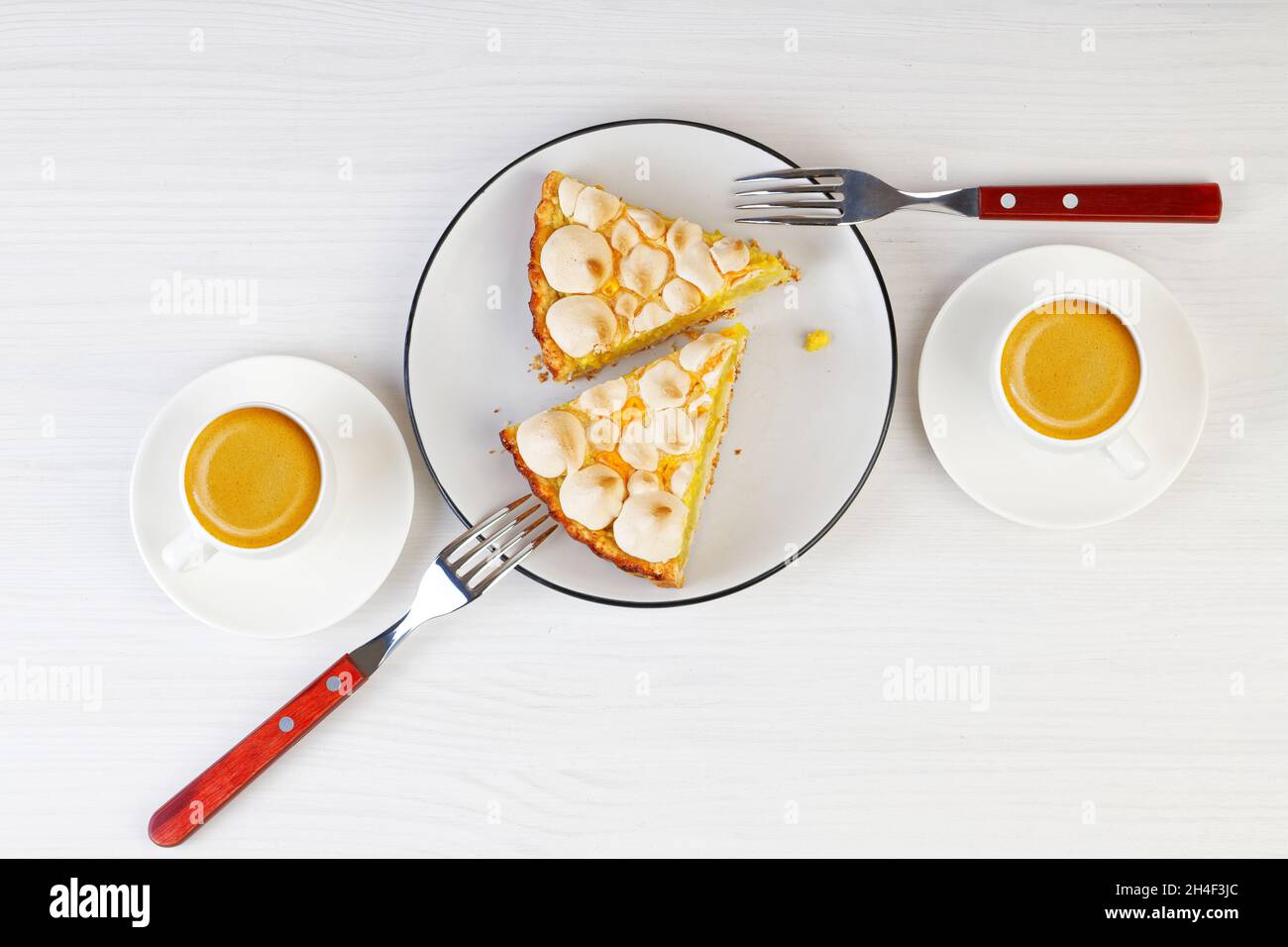 Deux morceaux de tarte maison décorés de meringue et deux tasses d'espresso sur une table en bois blanc.Vue de dessus. Banque D'Images Deux morceaux de tarte maison décorés de meringue et deux tasses d'espresso sur une table en bois blanc.Vue de dessus. Banque D'Images