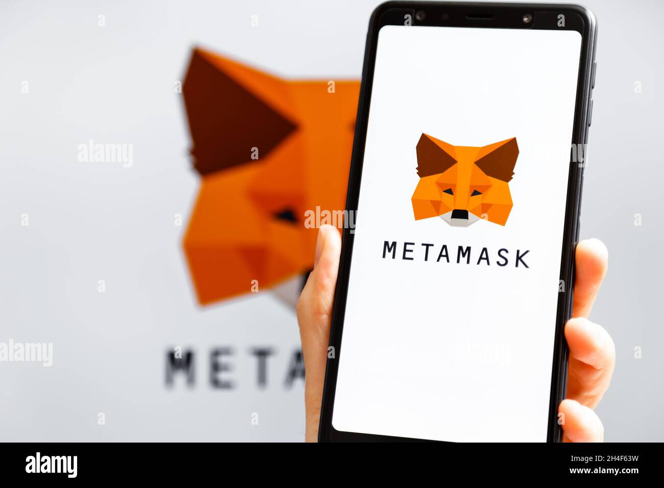 Ukraine, Odessa - octobre, 9 2021: Main tenant mobile avec l'application MetaMask fonctionnant à l'écran de smartphone avec le logo MetaMask en arrière-plan.MetaMask l'est Banque D'Images