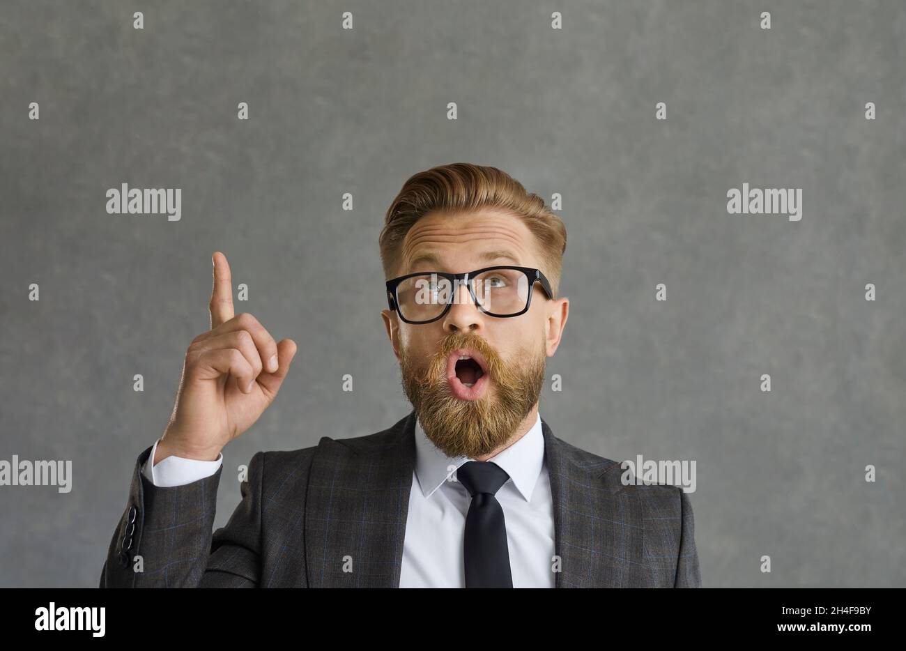 Portrait de l'homme en costume élégant et lunettes pointant vers le haut frappé par une idée d'affaires étonnante Banque D'Images
