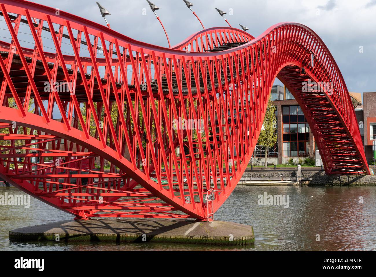Amsterdam, pays-Bas-Mai 2021: Vue latérale du serpent de métal rouge comme Pythonbrug avec des marches en bois qui est une passerelle traversant le canal Banque D'Images