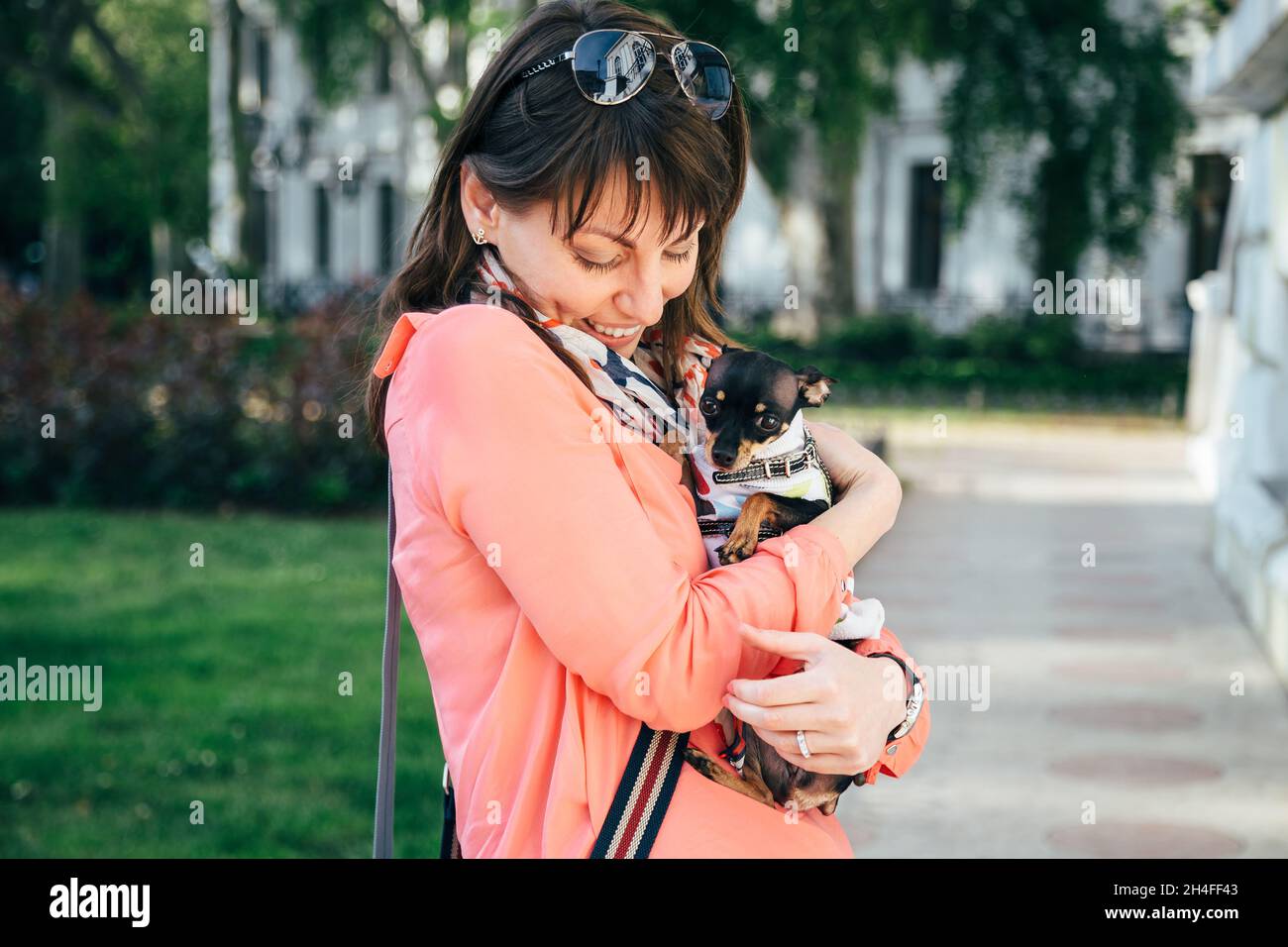 Bonne jeune femme caucasienne embrassant son petit chien, russe Toy Terrier ou russe Toy Terrier, vêtu d'un costume d'automne.Animaux de compagnie adorés Banque D'Images