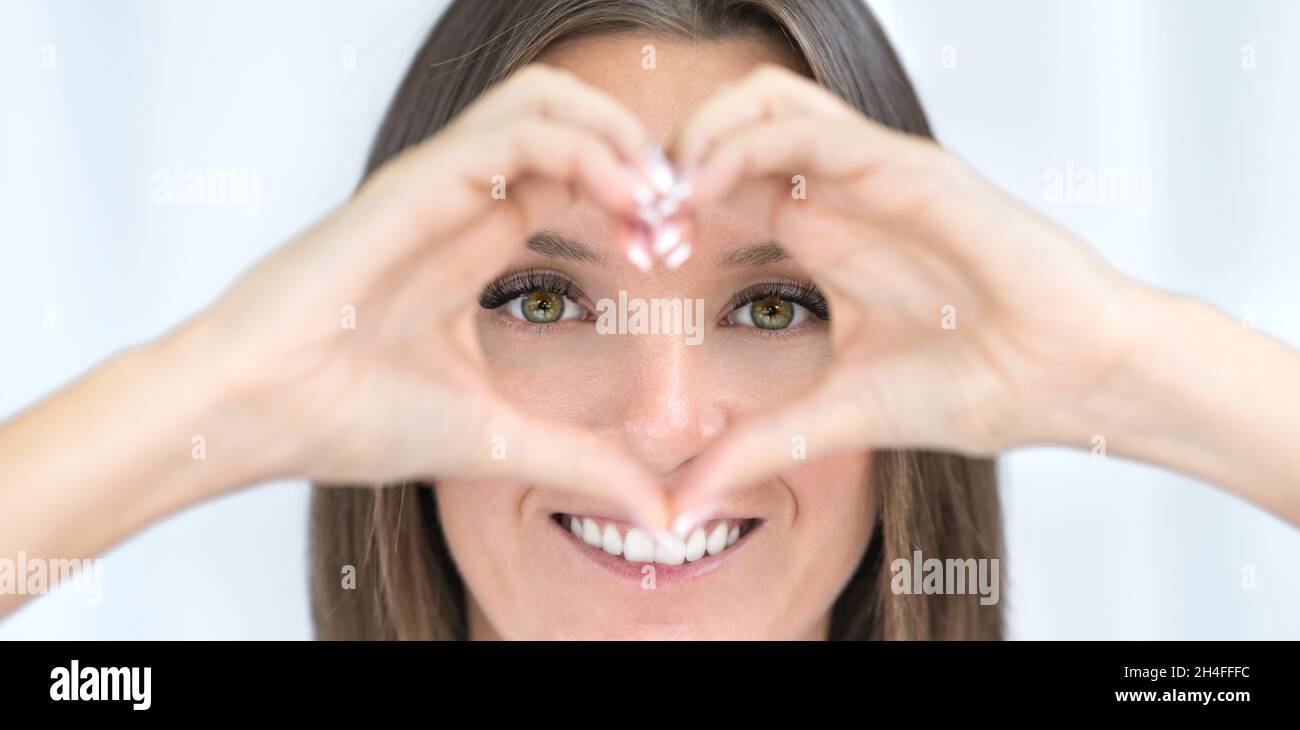 Soins des yeux.Des yeux sains.Une jeune femme avec une vision parfaite fait le cœur avec les mains.Concept d'ophtalmologie Banque D'Images