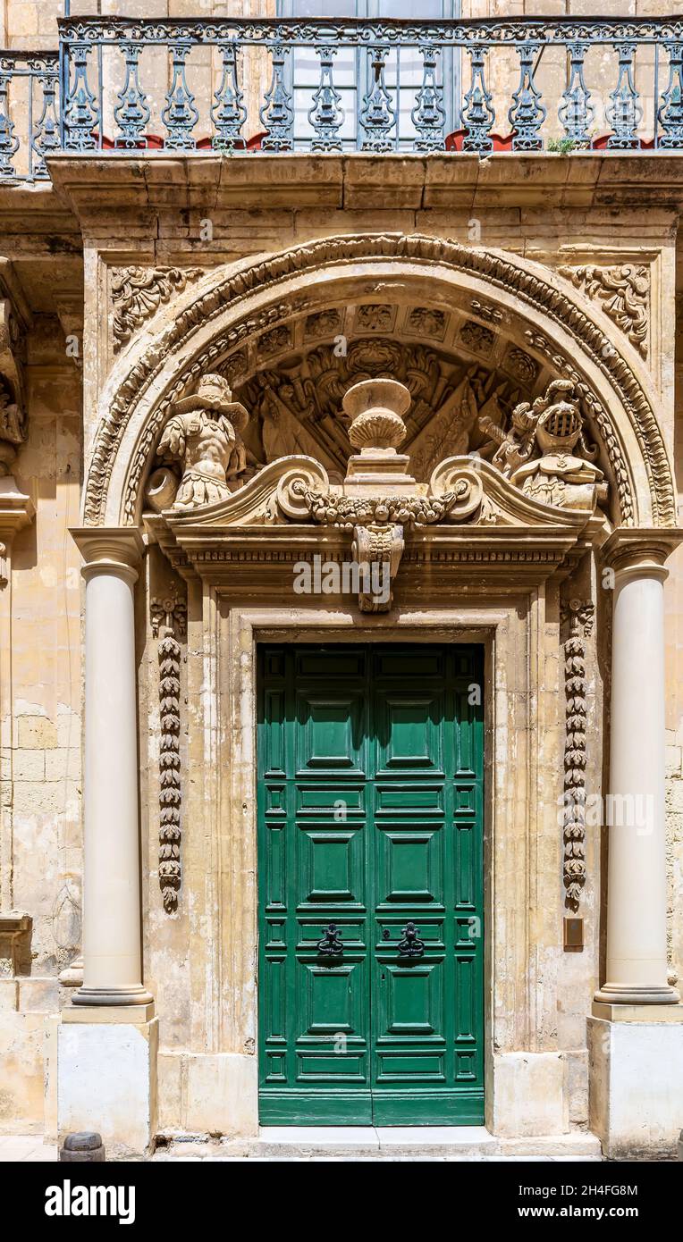 Porte verte en bois décorée dans un cadre historique dans une entrée en pierre à Mdina, Malte.Avec des sculptures en pierre voûtées au-dessus.Thème architectural. Banque D'Images