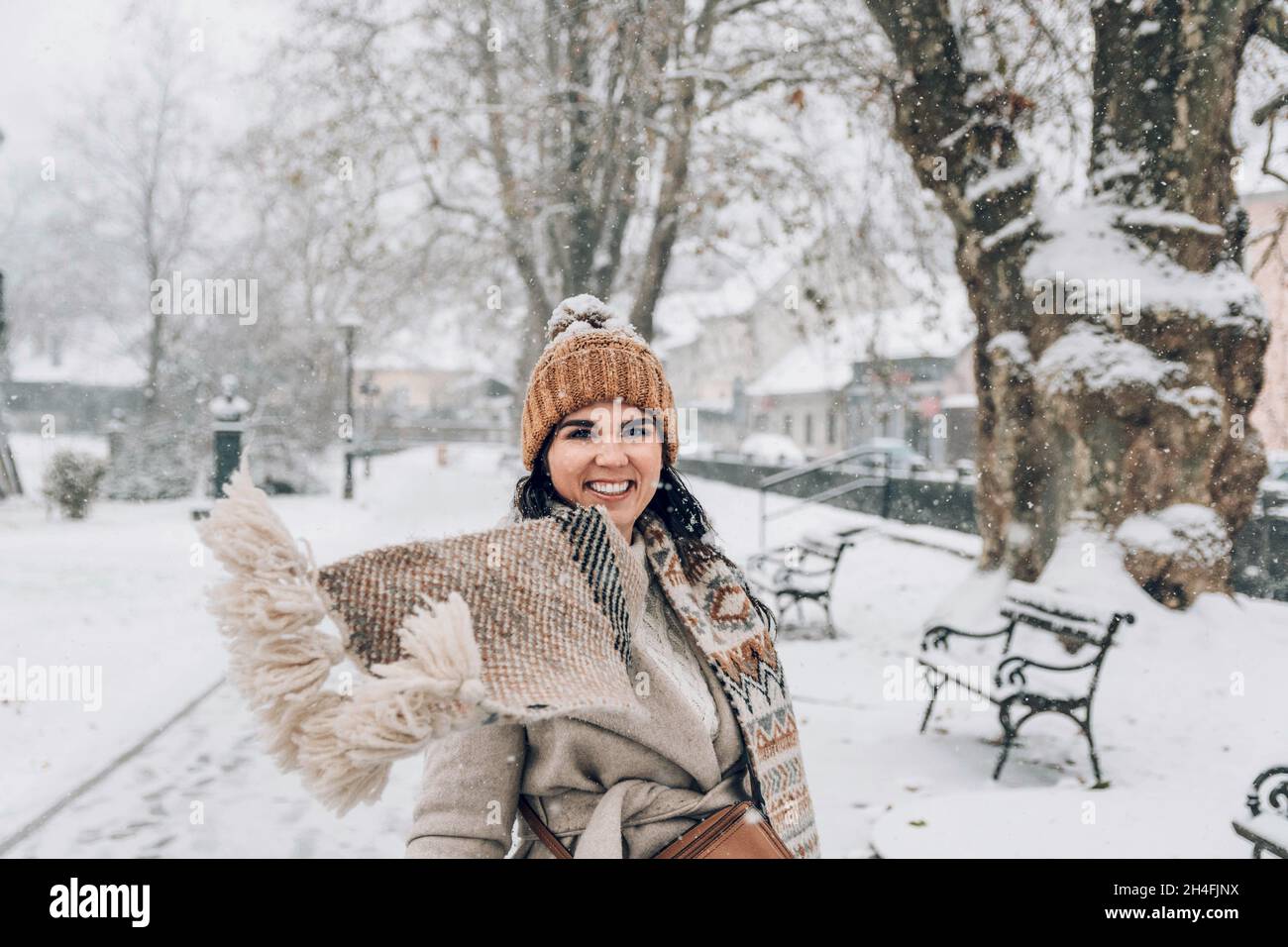 Portrait d'une belle jeune femme en vêtements d'hiver élégants debout dans un parc enneigé. Banque D'Images