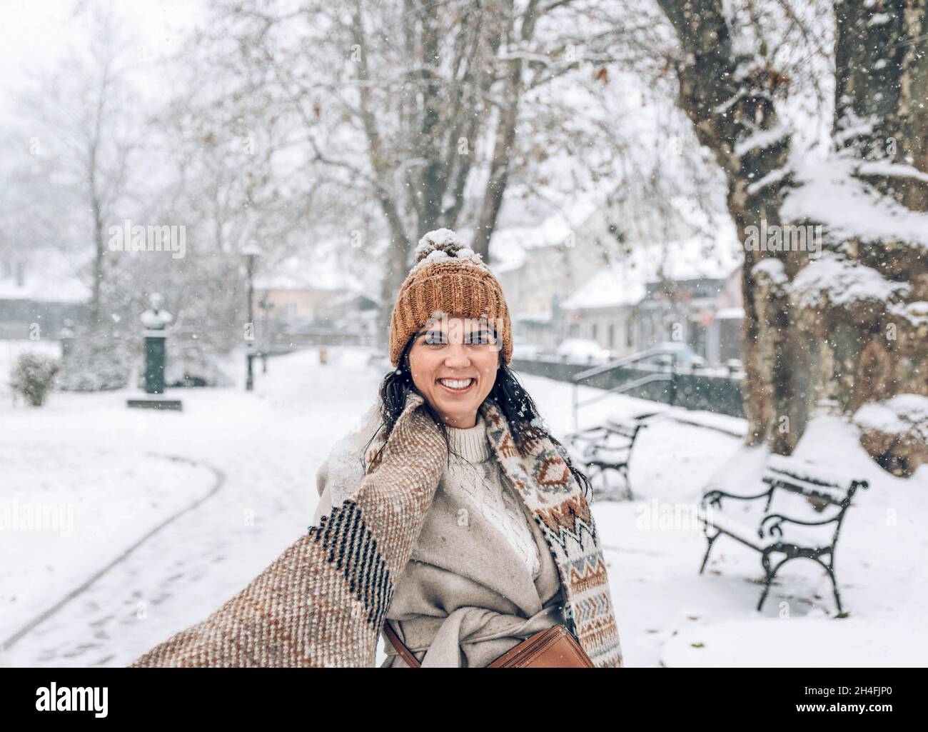 Portrait d'une belle jeune femme en vêtements d'hiver élégants debout dans un parc enneigé. Banque D'Images