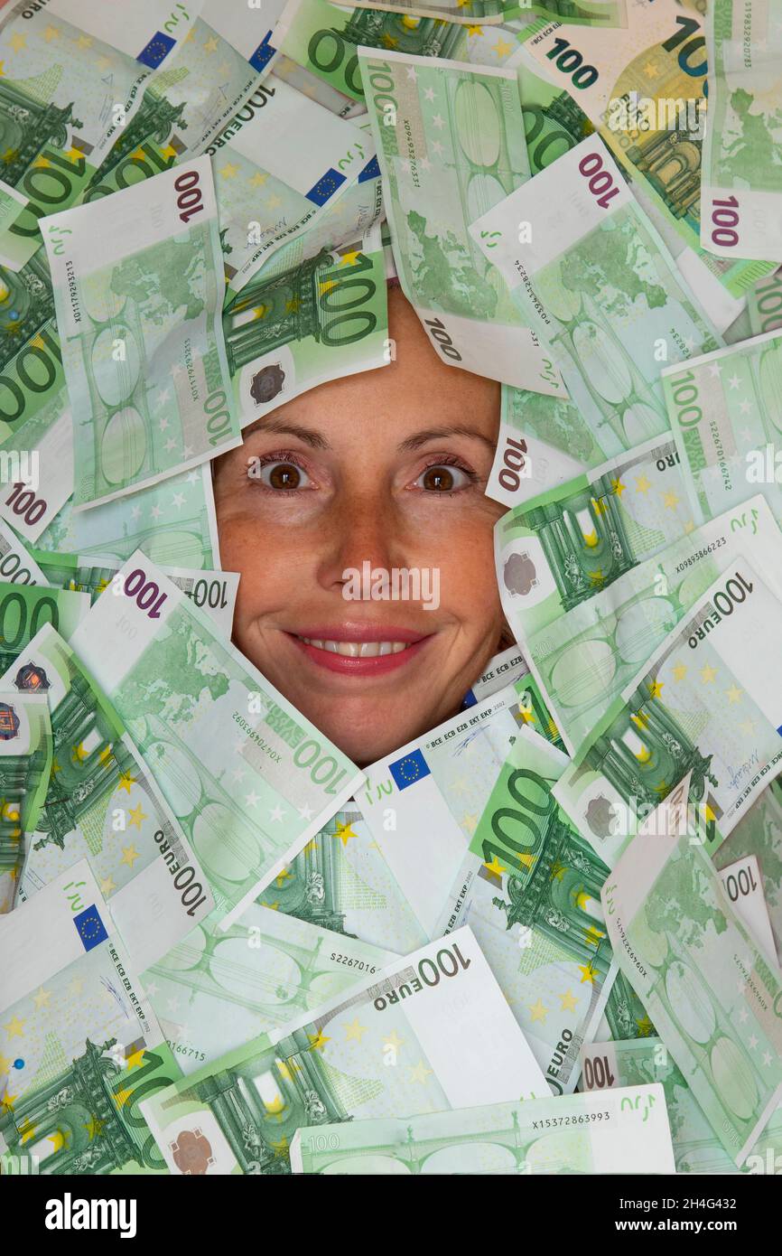 Concept de vie pleine d'argent, le visage souriant d'une femme entouré de 100 euros de factures Banque D'Images