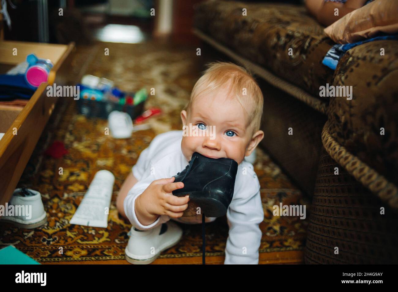 Bébé enfant garçon de six mois prend sa chaussure dans la bouche Banque D'Images