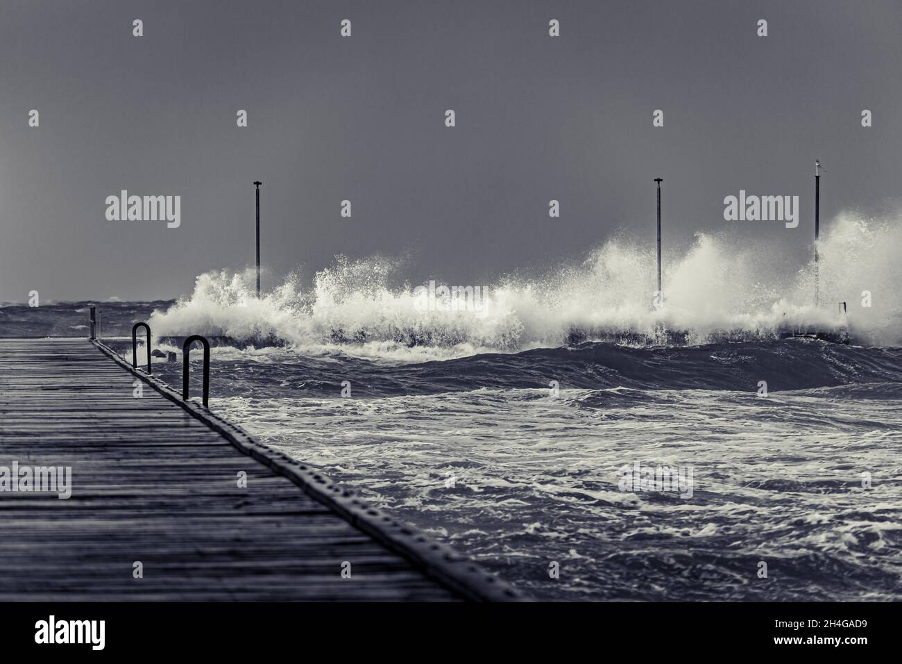 Vagues déglutiant fin de Frankston quai lors d'une sombre journée de tempête en noir et blanc Banque D'Images