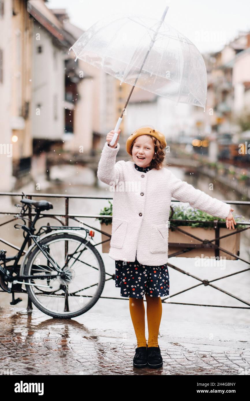 Belle fille gaie dans un manteau avec un parapluie transparent à  Annecy.France.La fille lève gaiement un parapluie sous la pluie Photo Stock  - Alamy