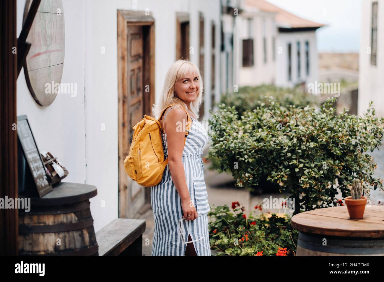 Une blonde dans une sundress avec un sac à dos marche le long de la rue de la vieille ville de Garachico sur l'île de Tenerife.Espagne, îles Canaries Banque D'Images