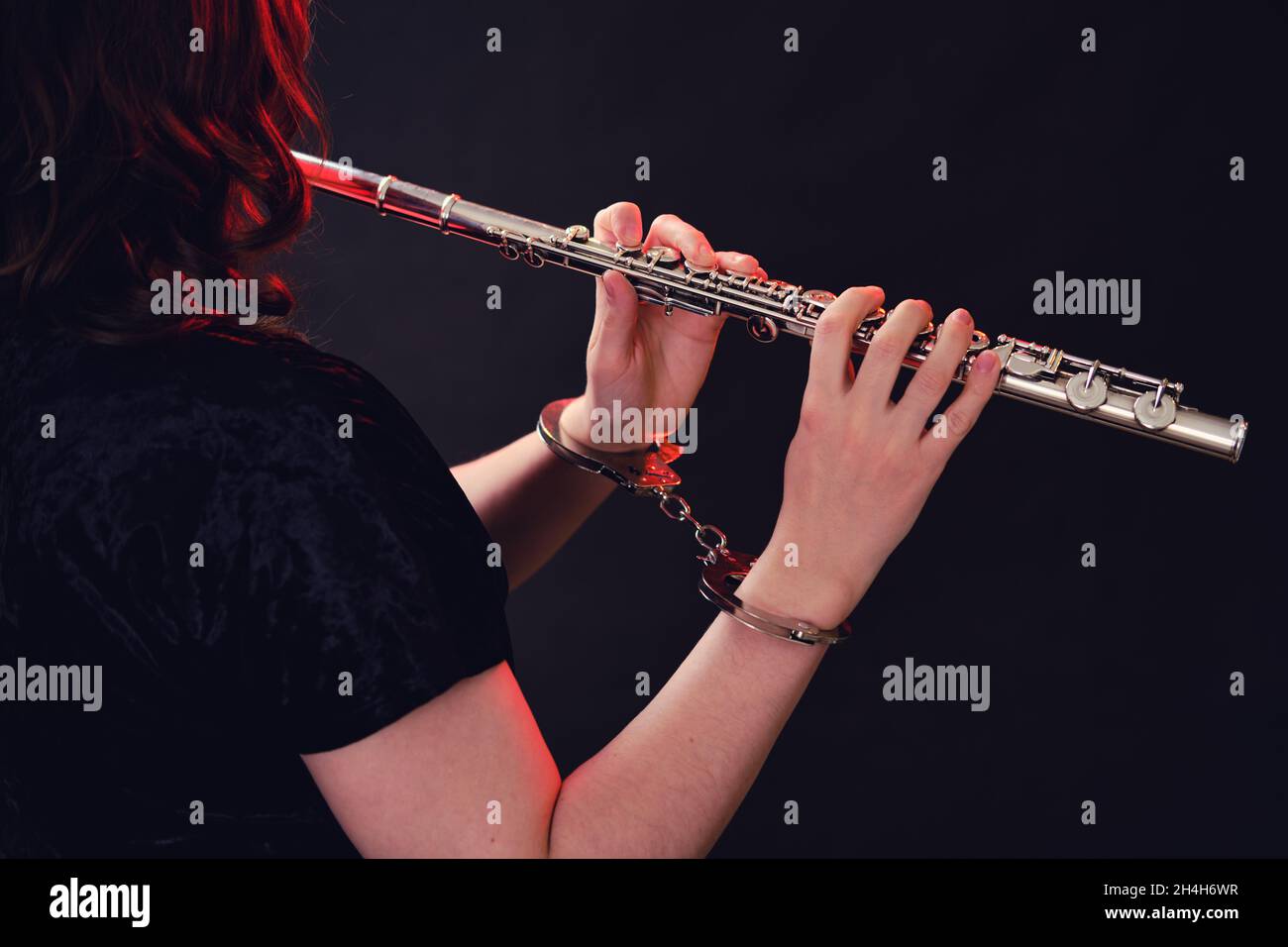 Mains d'une femme musicienne avec une flûte à main menottée sur fond noir de studio.Problèmes de jouer à des concerts, le concept de non-f Banque D'Images