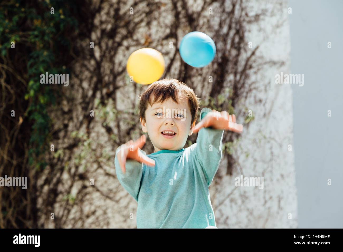 Enfant jetant des balles en plastique de couleur avec ses mains. Banque D'Images