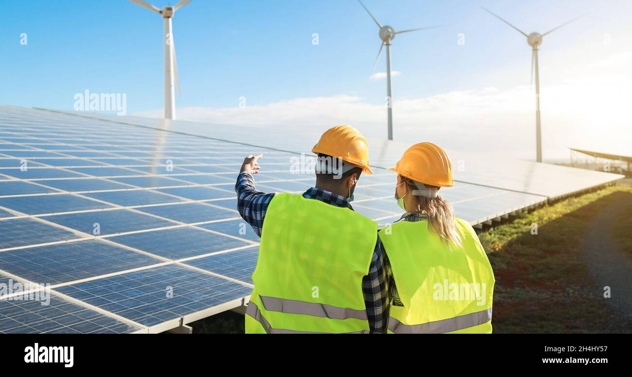 Personnes travaillant pour une ferme d'énergie alternative tout en portant des masques de sécurité - Focus sur les casques Banque D'Images