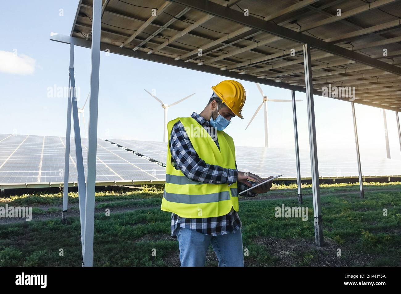 Jeune homme travaillant avec une tablette numérique dans un parc éolien à énergie renouvelable - Focus on face Banque D'Images