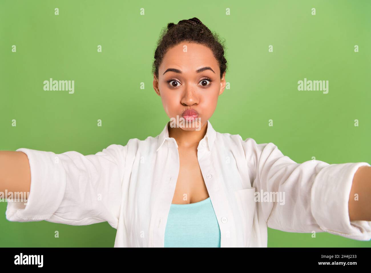 Photo portrait femme avec coiffure de pain envoi air baiser prenant selfie isolé pastel couleur vert fond Banque D'Images
