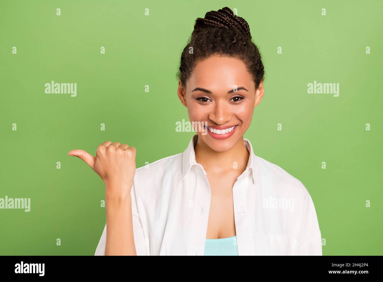Photo portrait femme avec un pain coiffure pointant Copyspace avec le pouce isolé pastel couleur vert fond Banque D'Images