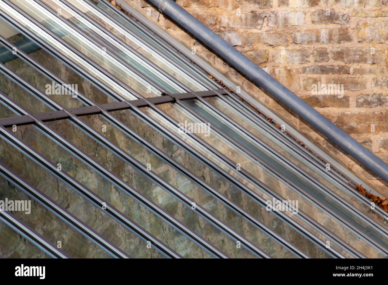 Toit en verre reflétant un mur en pierre naturelle Banque D'Images