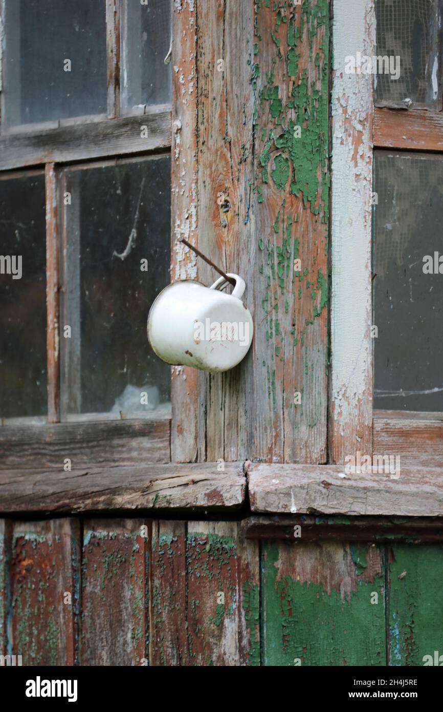 Coupe en émail suspendue sur un clou à l'extérieur d'une maison abandonnée à Tchernobyl Banque D'Images