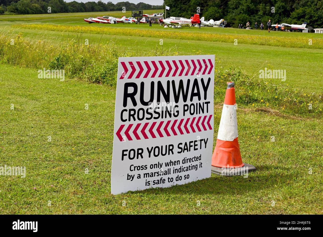 Popham, Angleterre - août 2021 : panneau d'avertissement pour les personnes qui souhaitent traverser la piste d'herbe à l'aérodrome de Popham près de Basingstoke. Banque D'Images