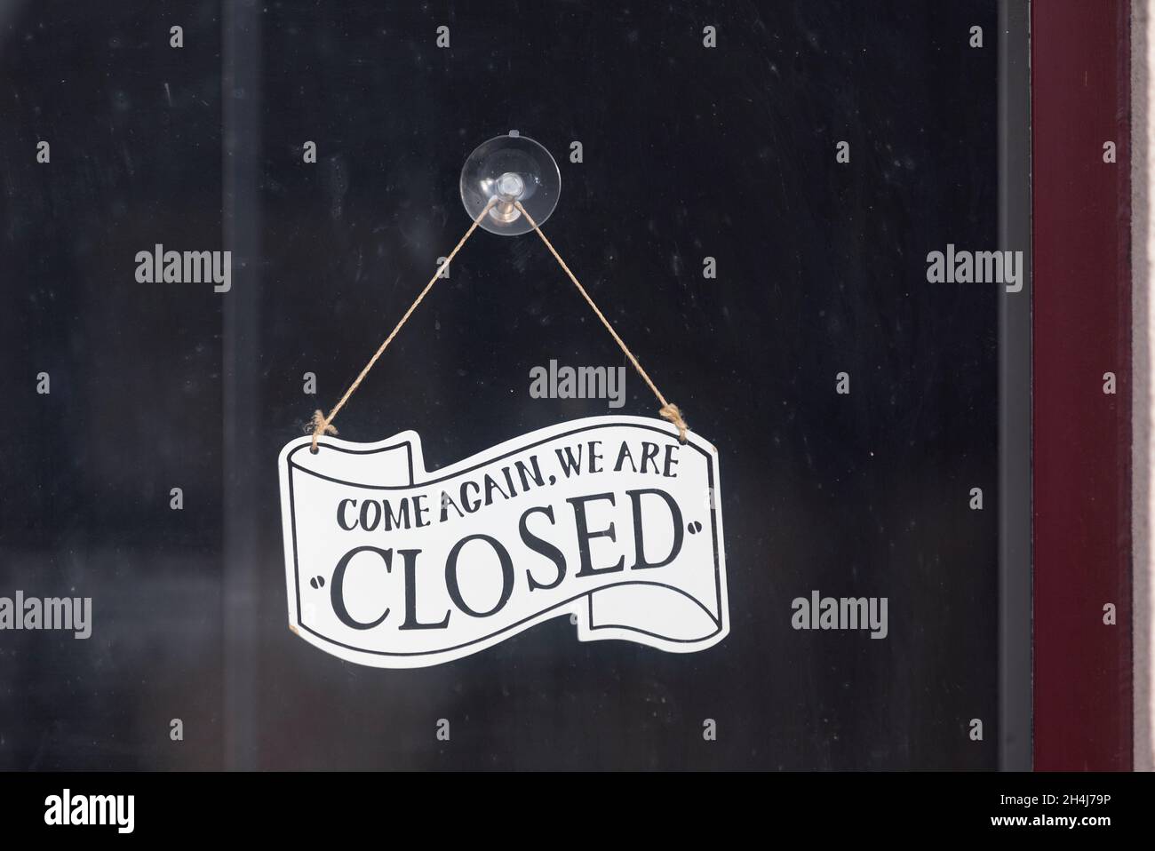 Gros plan sur un panneau attaché à une porte vitrée disant - revenez, nous sommes fermés-. Banque D'Images