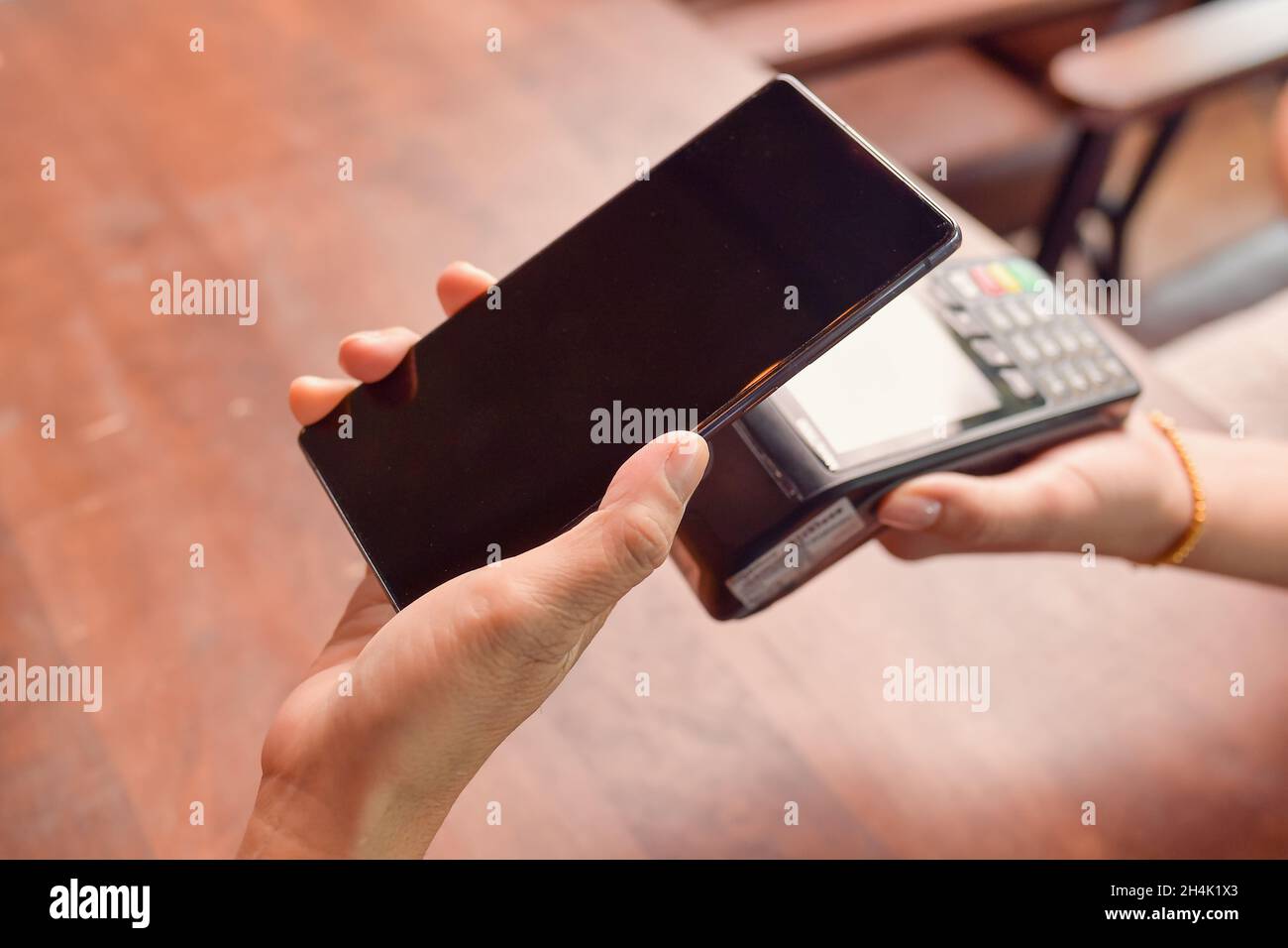 Personne effectuant un paiement sans contact avec un téléphone mobile sur un lecteur de carte de crédit Banque D'Images