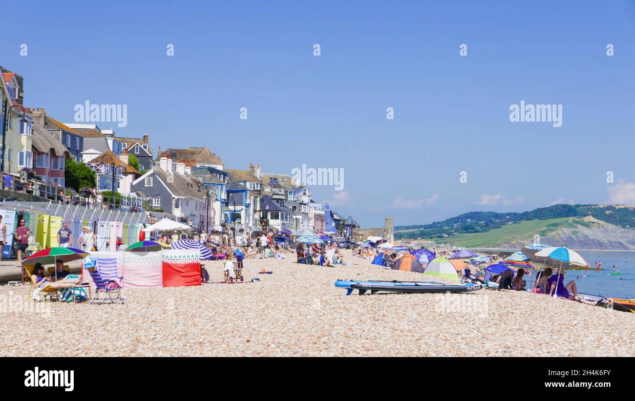 Familles sur la plage avec des tentes de plage pop up transats parasols de plage et paddle-boards sur la plage de sable à Lyme Regis Dorset Angleterre GB Europe Banque D'Images