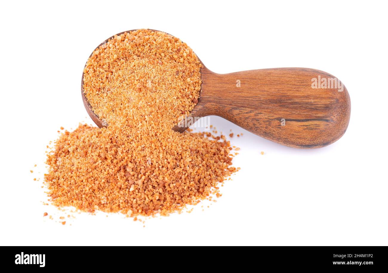 Sucre de noix de coco isolé sur fond blanc.Faire revenir le sucre de noix de coco non raffiné dans une cuillère en bois. Banque D'Images