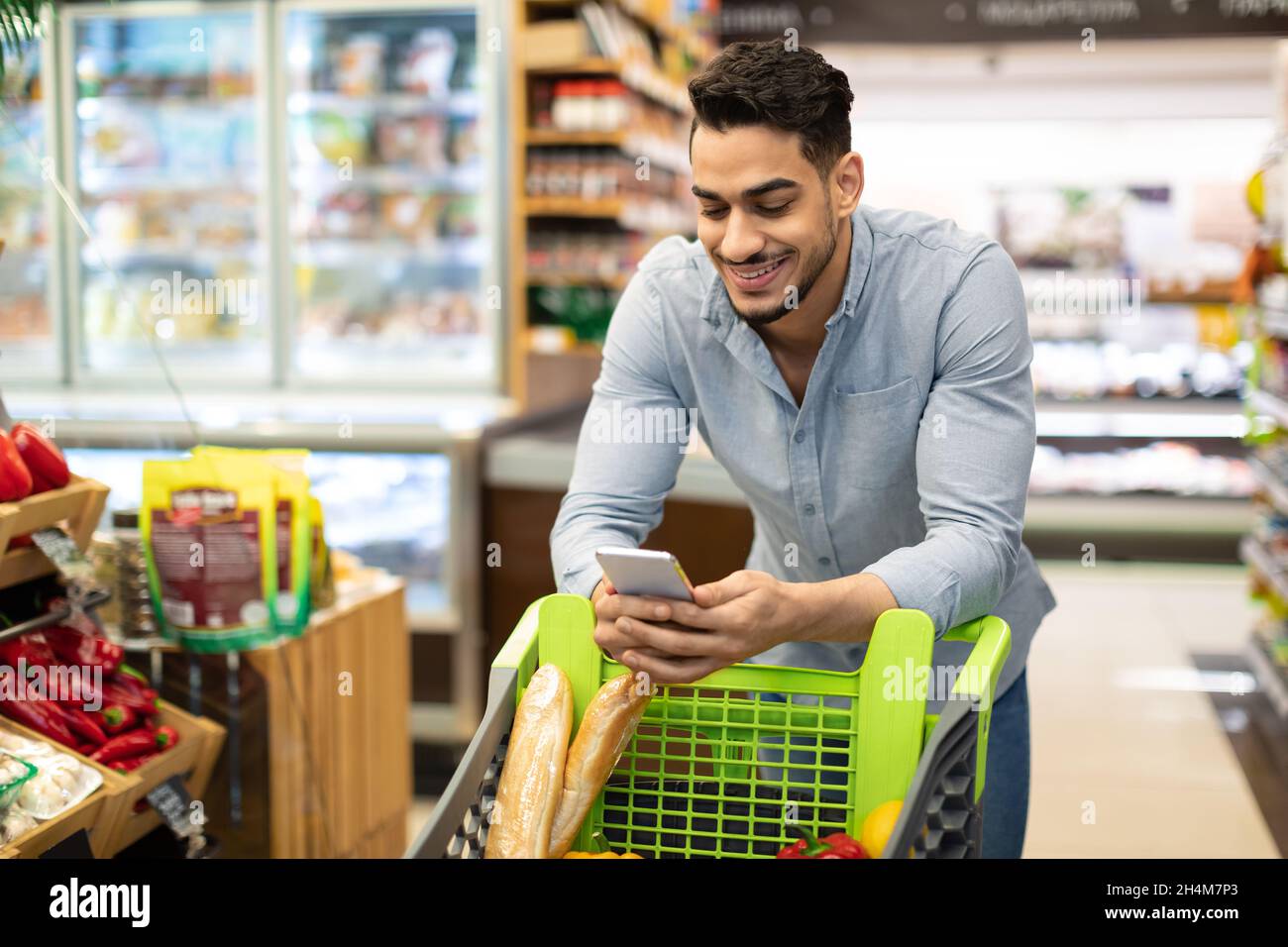 Arabe Homme Acheteur avec telephone Acheter des provisions en ligne Shopping dans application mobile debout avec Panier de magasin dans un supermarche moderne.Guy Purchasing Foo Photo Stock Alamy