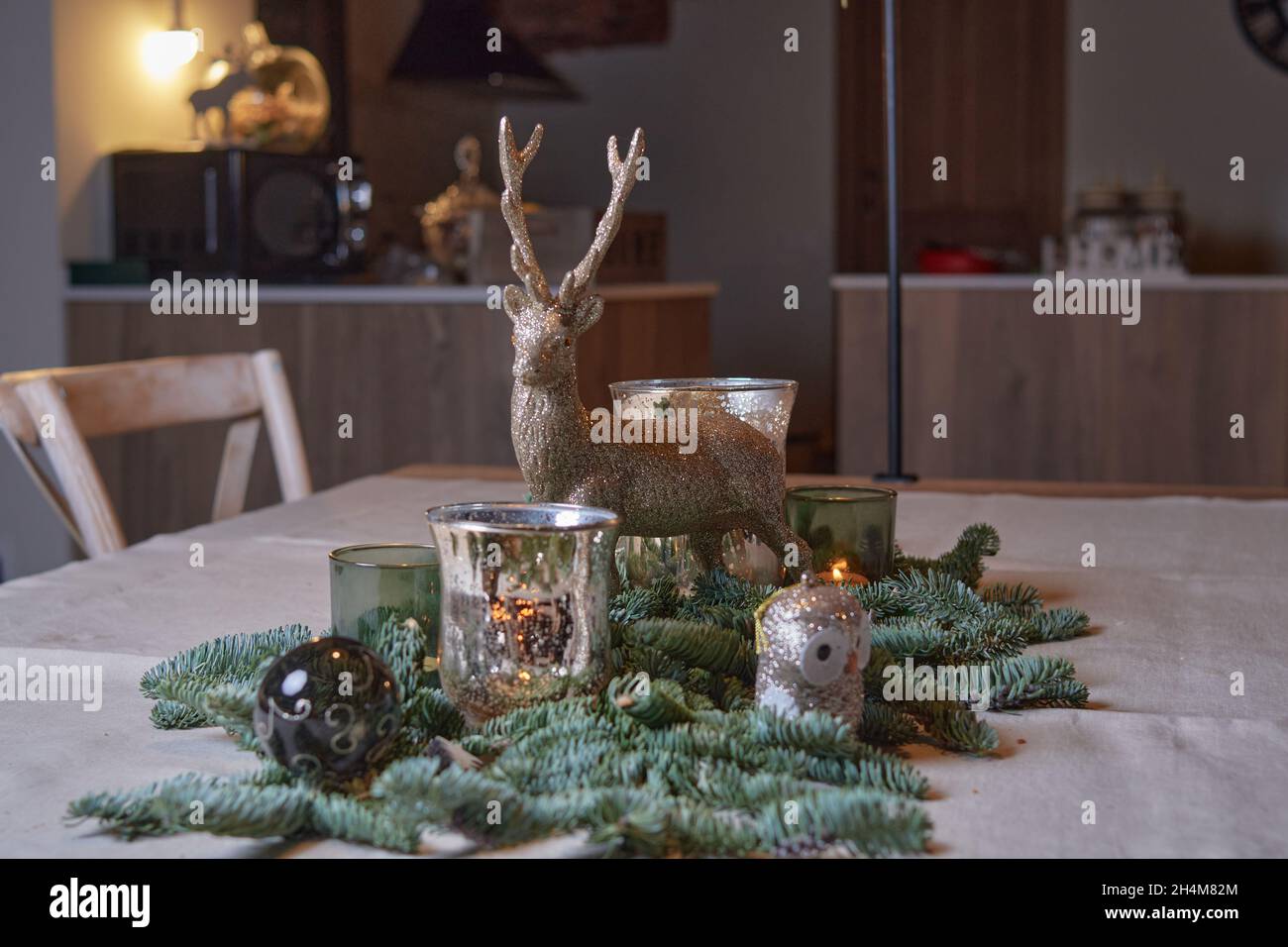 Pièce maîtresse de Noël de style rustique préparée pour un dîner de Noël en famille avec un renne et des bougies allumées sur une table en bois. Concept noël Banque D'Images