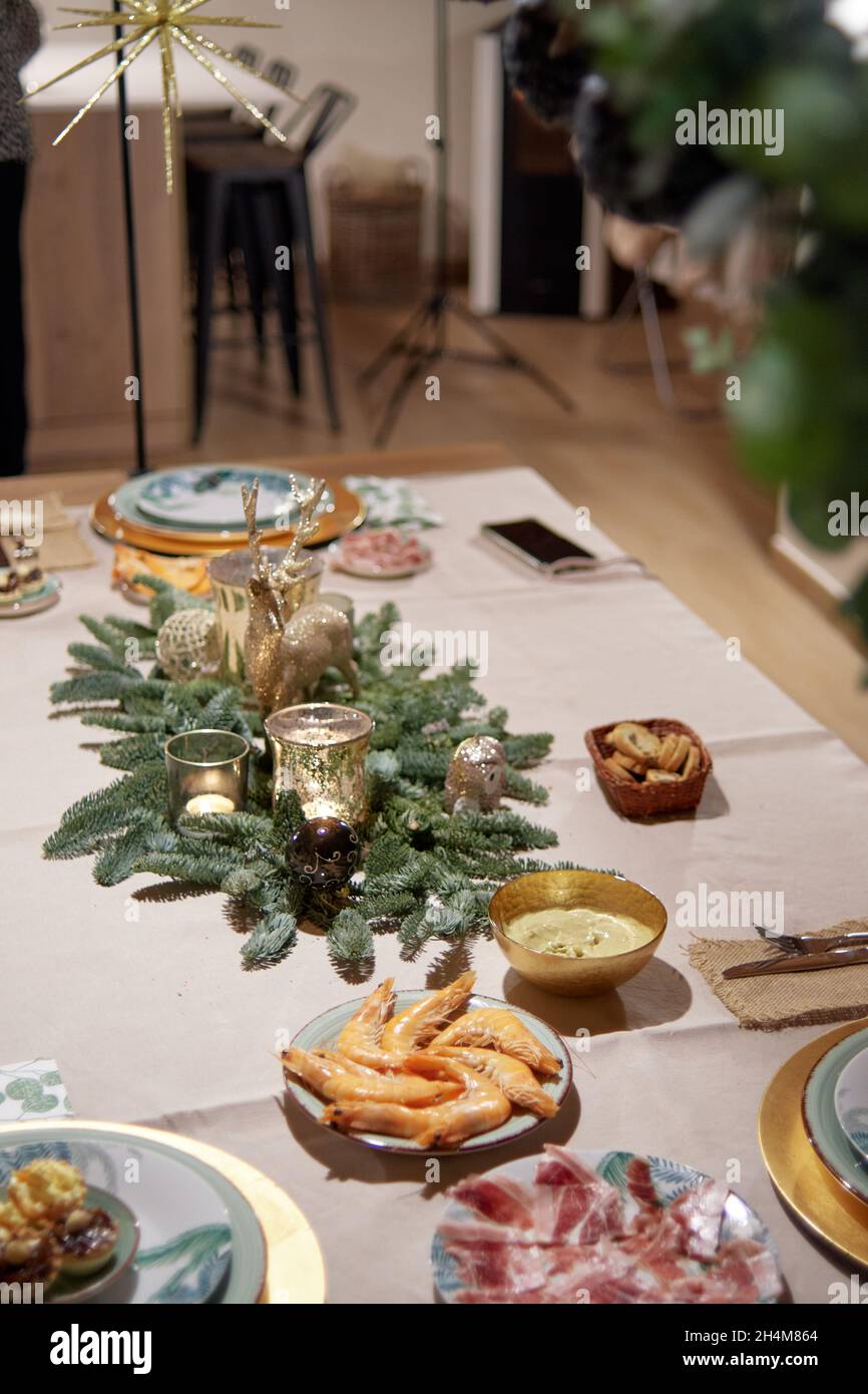Table décorée de décorations de Noël préparée pour le dîner de la veille de Noël en famille.Assortiment de canapés, jambon ibérique et crevettes. Tradition et famille Banque D'Images