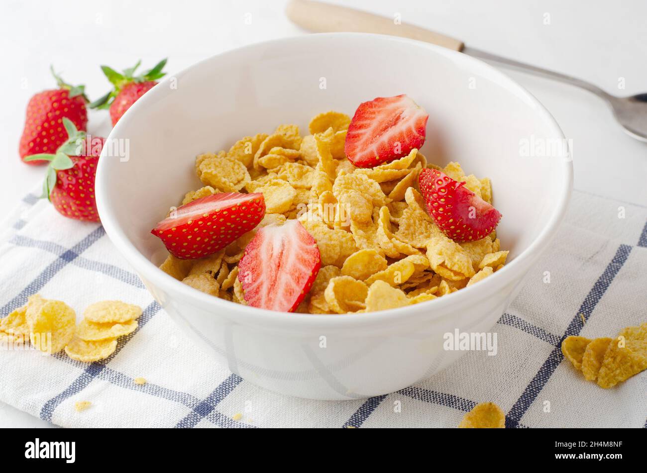 Céréales de maïs saines avec lait pour le petit déjeuner avec fraise de fruits dans la cuisine Banque D'Images