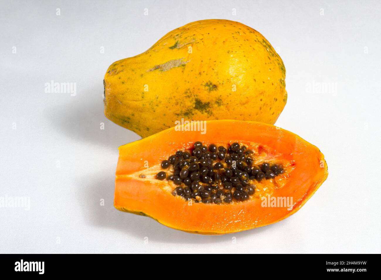 Demi-coupe de papaye mûre fraîche avec des graines isolées sur fond blanc.Mise au point sélective. Banque D'Images