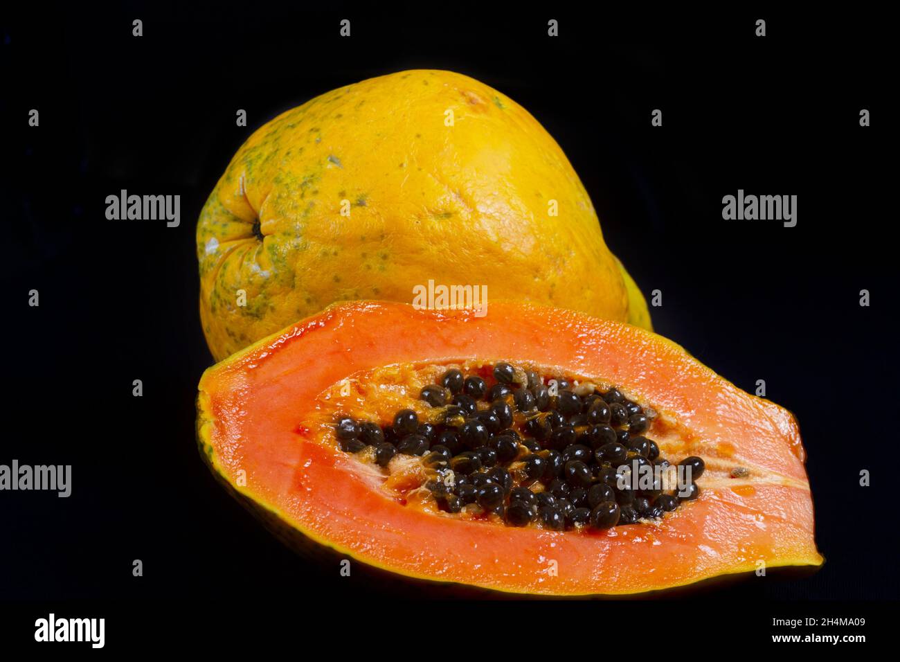 Demi-coupe de papaye mûre fraîche avec des graines isolées sur fond sombre.Mise au point sélective. Banque D'Images