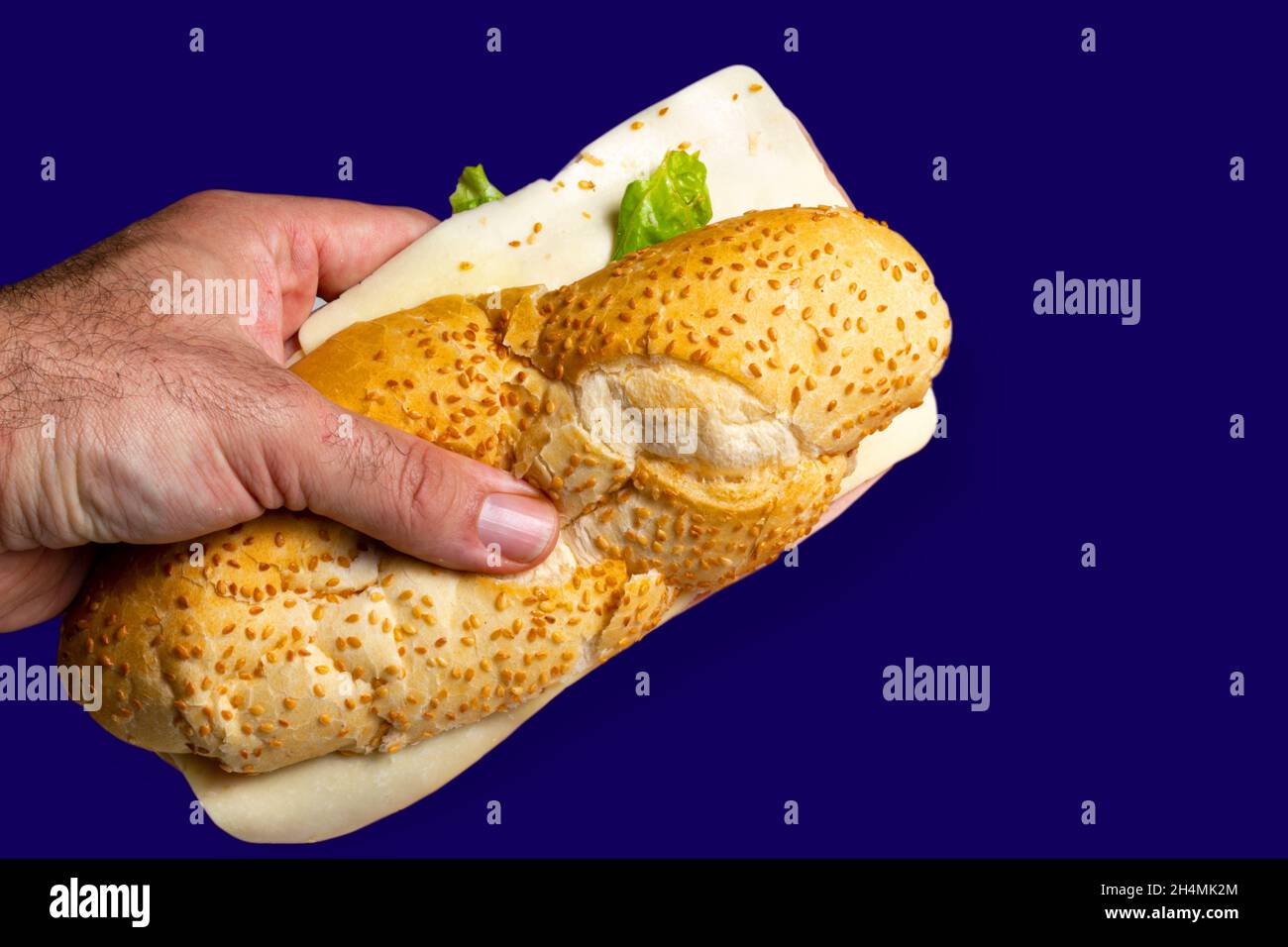 Main mâle tenant un sandwich naturel sur fond bleu.Mise au point sélective. Banque D'Images