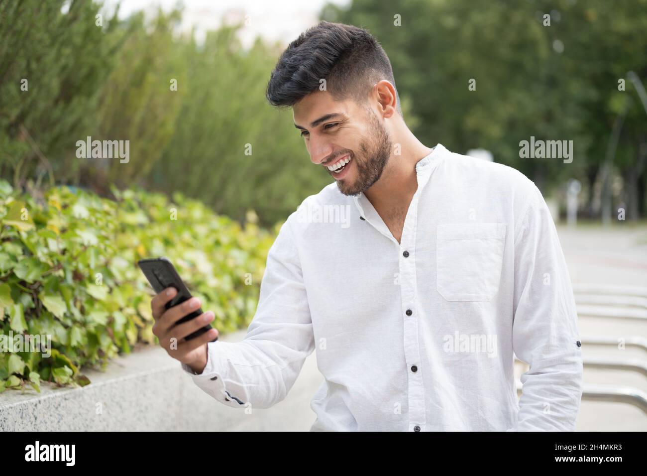 Beau mélange race jeune homme, souriant, en utilisant un téléphone mobile à l'extérieur.Photo de haute qualité Banque D'Images