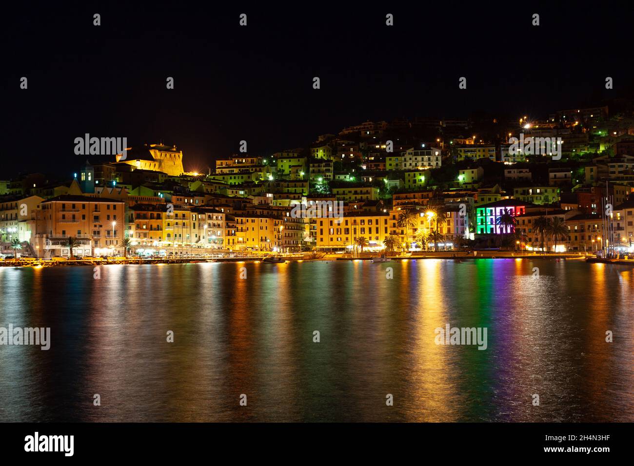Petite ville Porto Santo Stefano la nuit, Monte Argentario, Toscane, Italie, avec des lumières de la ville et des réflexions sur l'eau Banque D'Images