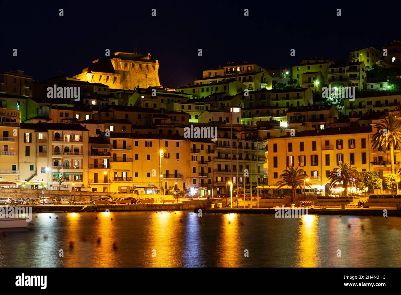 Petite ville Porto Santo Stefano la nuit, Monte Argentario, Toscane, Italie, avec des lumières de la ville et des réflexions sur l'eau Banque D'Images