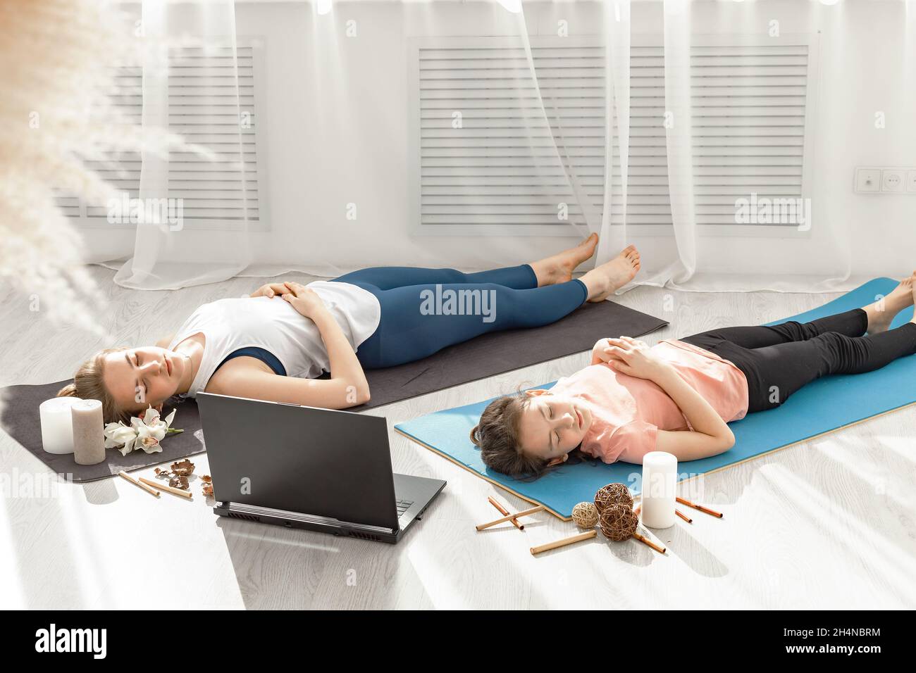 Deux jeunes filles sportives qui font du hatha yoga ensemble dans un studio lumineux moderne.Ils sont sur le sol et méditent avec leurs yeux.Cours de yoga Banque D'Images