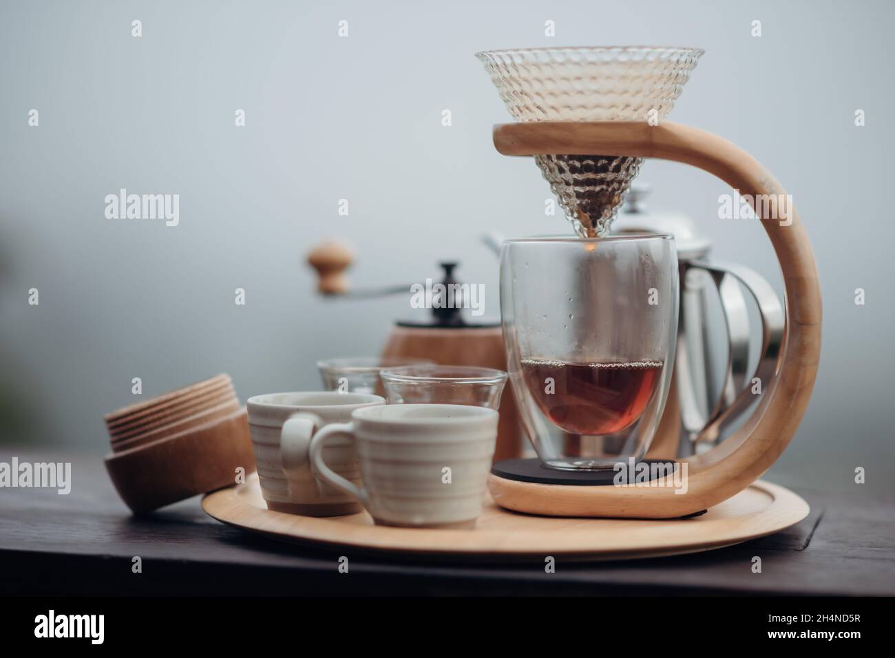 Un nécessaire à café goutte-à-goutte avec une bouilloire en acier, un verre et une cafetière goutte-à-goutte dans un style minimaliste avec un fond de brouillard et de nature. Banque D'Images Un nécessaire à café goutte-à-goutte avec une bouilloire en acier, un verre et une cafetière goutte-à-goutte dans un style minimaliste avec un fond de brouillard et de nature. Banque D'Images