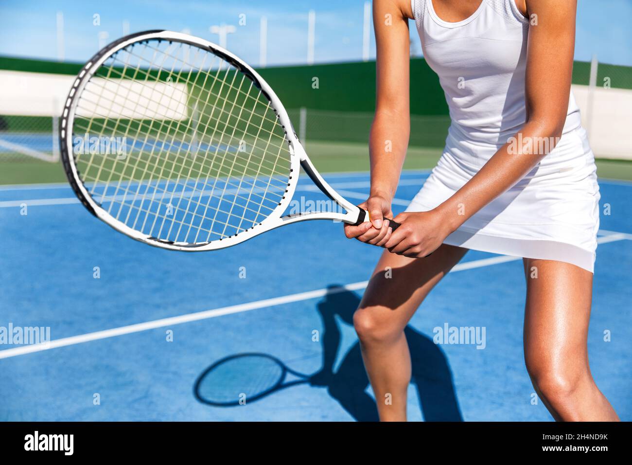 Joueur de tennis femme prêt à jouer à un jeu sur un terrain bleu dur tenant une raquette en position portant une jupe habillée blanche.Athlète féminine sport fille en été Banque D'Images