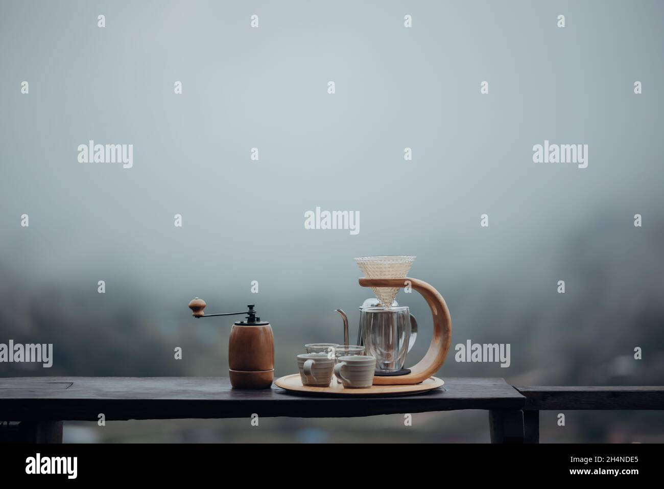 Un nécessaire à café goutte-à-goutte avec une bouilloire en acier, un verre et une cafetière goutte-à-goutte dans un style minimaliste avec un fond de brouillard et de nature. Banque D'Images Un nécessaire à café goutte-à-goutte avec une bouilloire en acier, un verre et une cafetière goutte-à-goutte dans un style minimaliste avec un fond de brouillard et de nature. Banque D'Images