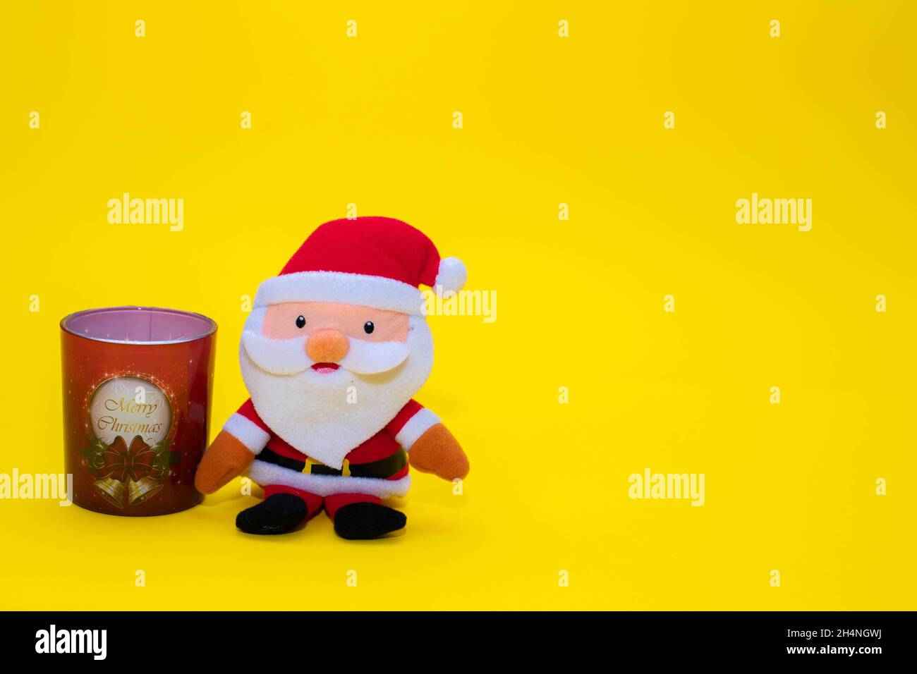 Drole De Pere Noel Bourre Et Une Bougie En Verre Sur Fond Jaune Photo Stock Alamy
