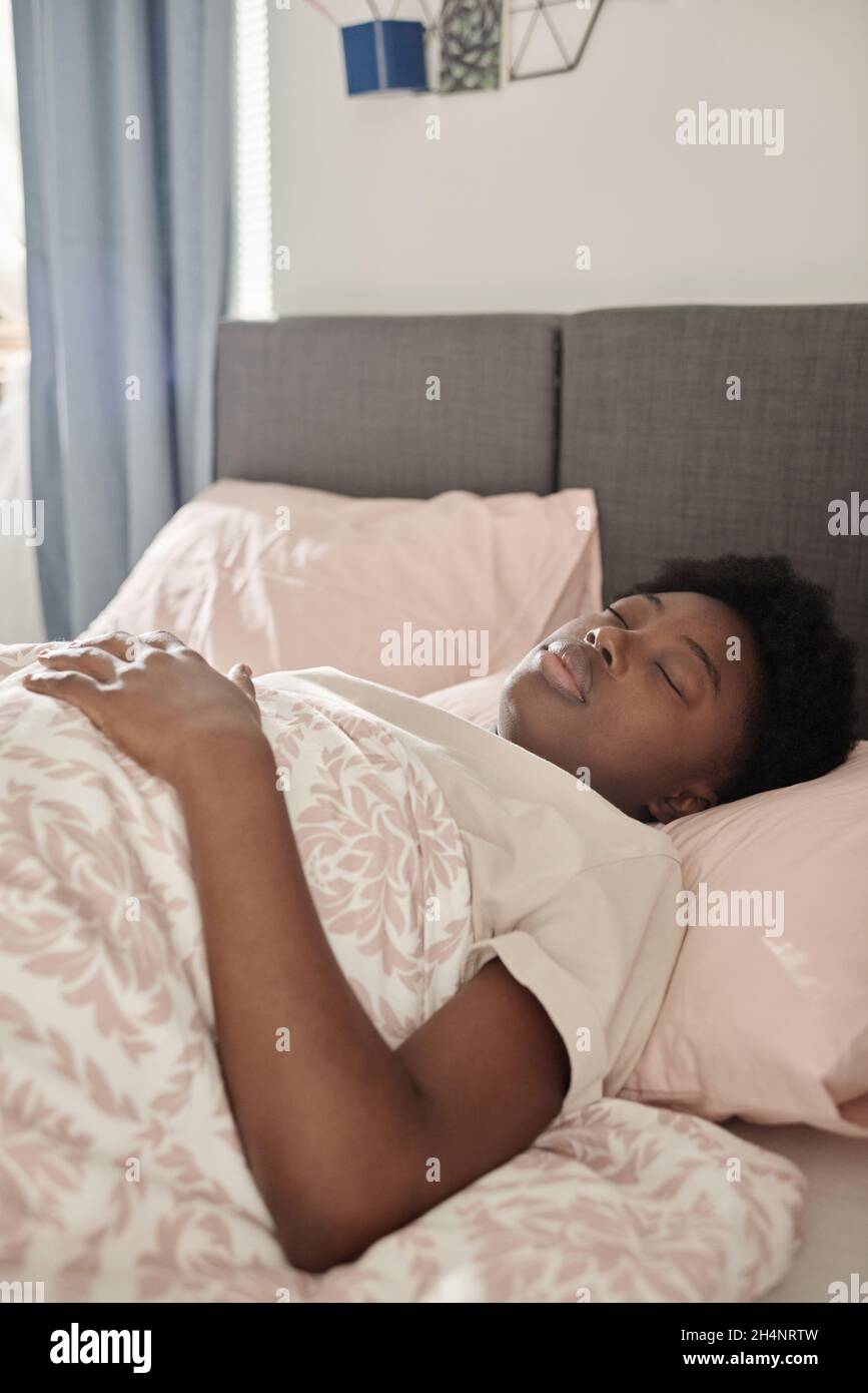 Une jeune femme africaine couchée à l'aise dans son lit avec les yeux  fermés et dormant Photo Stock - Alamy