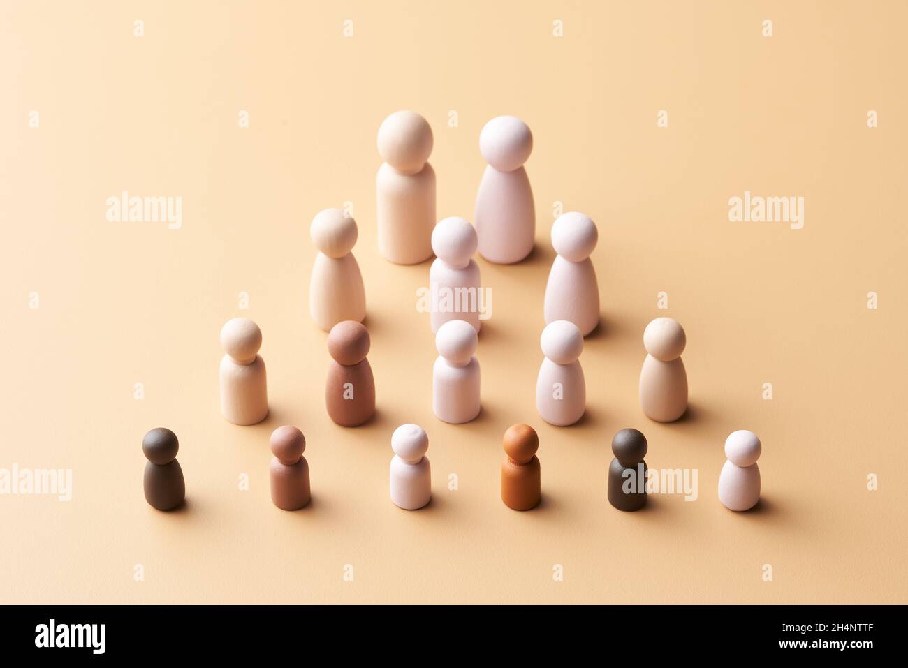 Des figurines simples ci-dessus de famille multiraciale et multigénérationnelle disposées en forme de pyramide sur fond beige Banque D'Images